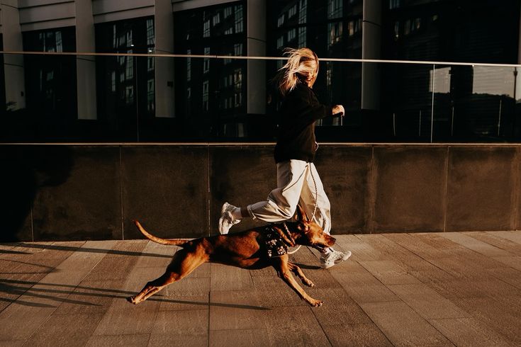 Young lady running with dog through urban landscape